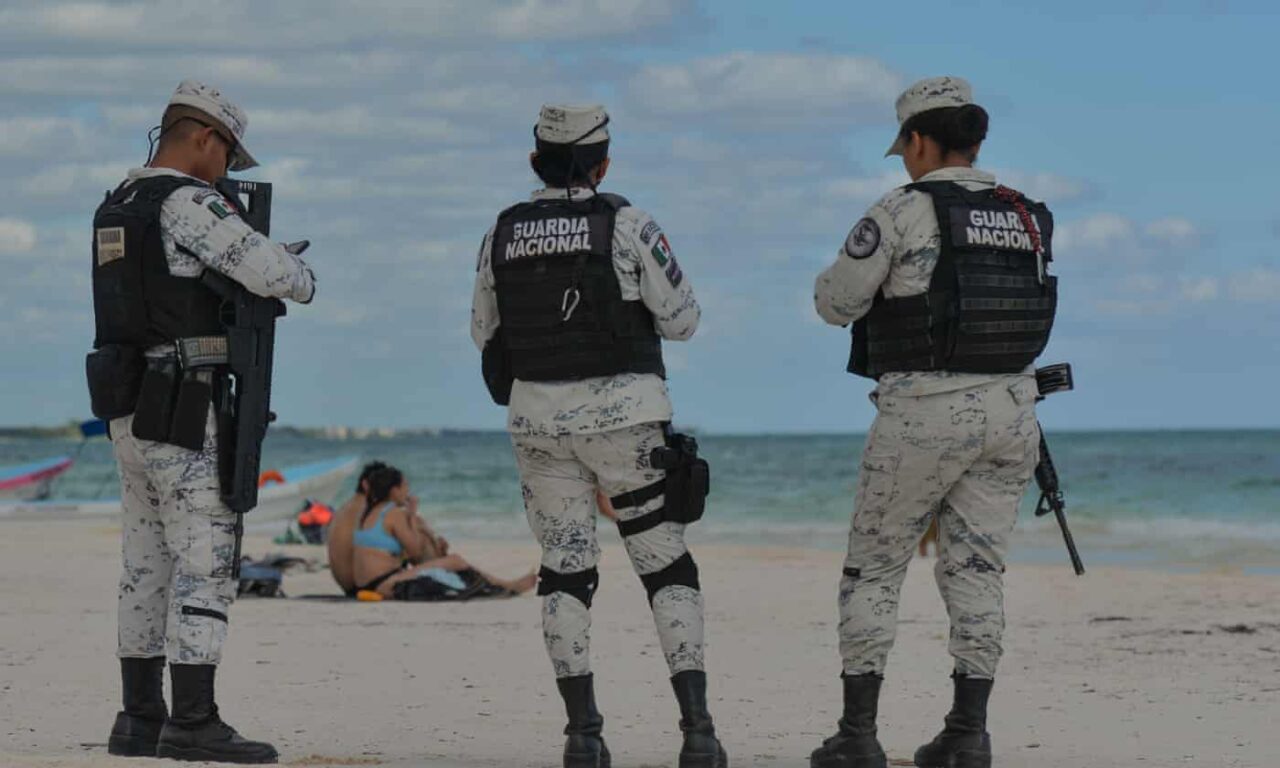 Los turistas pasean por la playa en medio de una batalla entre grupos criminales